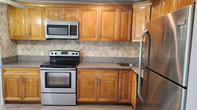 kitchen with backsplash, stainless steel appliances, and dark stone counters