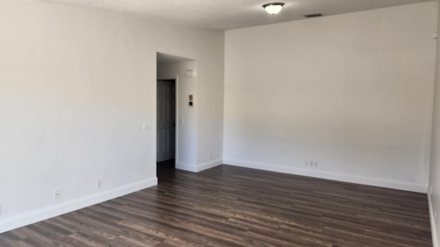 unfurnished room featuring a textured ceiling and dark hardwood / wood-style floors