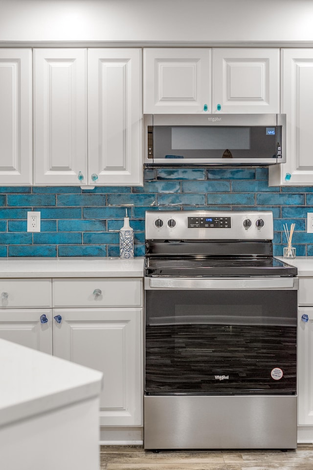 kitchen featuring white cabinets, electric range, and exhaust hood