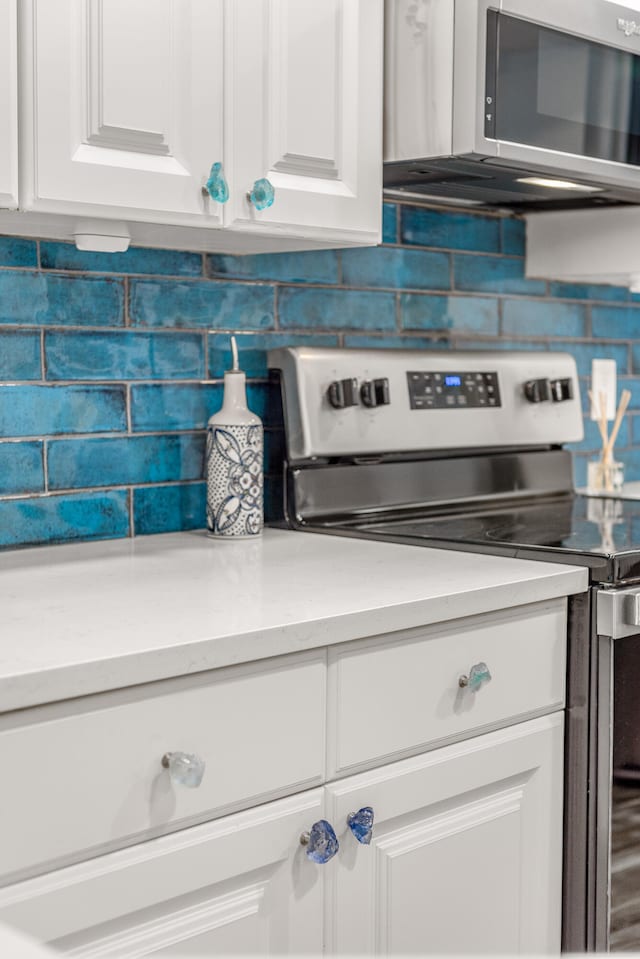 interior space featuring stainless steel appliances, white cabinetry, and tasteful backsplash