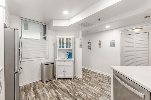 kitchen with light wood-type flooring, appliances with stainless steel finishes, and white cabinetry