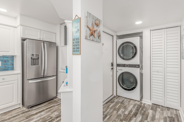 laundry area with hardwood / wood-style floors and stacked washer and dryer