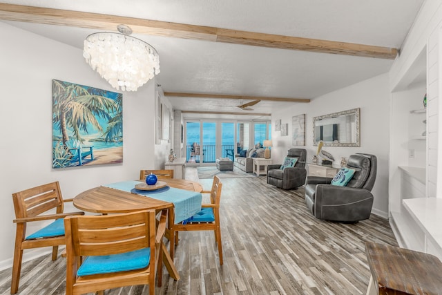 dining space with light wood-type flooring, beamed ceiling, ceiling fan with notable chandelier, and a textured ceiling