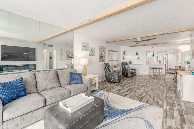 living room featuring ceiling fan with notable chandelier, a textured ceiling, and hardwood / wood-style floors