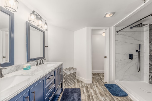 bathroom with tiled shower, vanity, and hardwood / wood-style floors