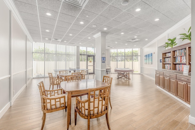 dining space with ornamental molding, light wood-type flooring, and ornate columns