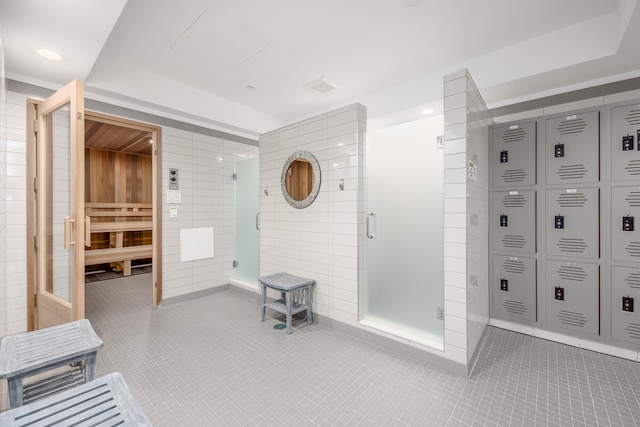 bathroom with tile walls, an enclosed shower, and tile patterned floors