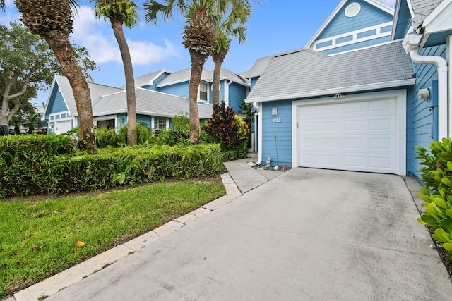 view of property featuring a garage and a front lawn