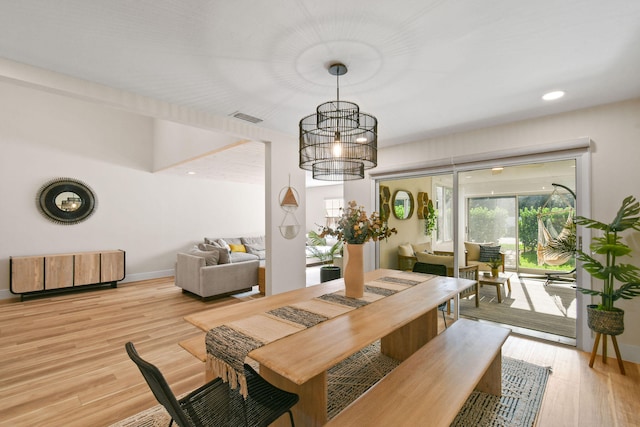 dining area with light wood-type flooring and a chandelier