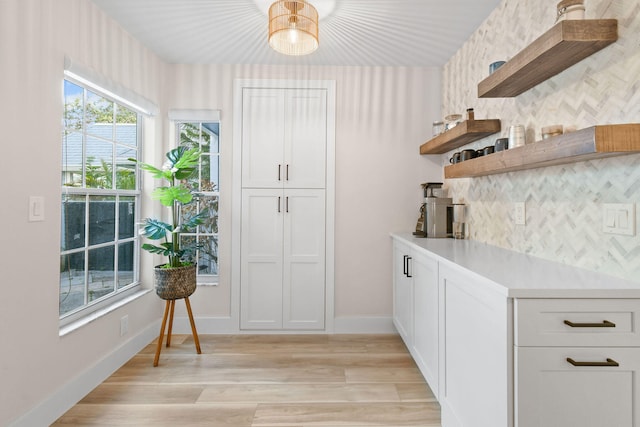 kitchen featuring decorative backsplash, white cabinetry, and light hardwood / wood-style flooring