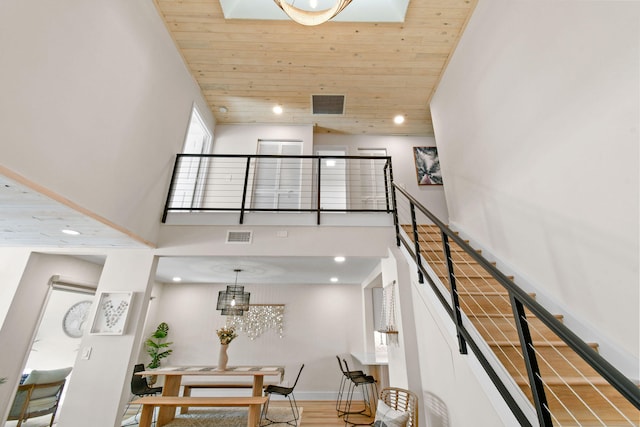 staircase with wooden ceiling, hardwood / wood-style flooring, a chandelier, and a high ceiling