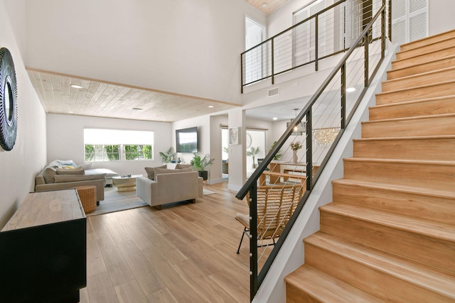 staircase with wood ceiling, a high ceiling, and wood-type flooring