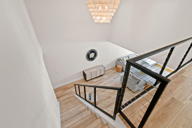 stairway with hardwood / wood-style flooring and an inviting chandelier