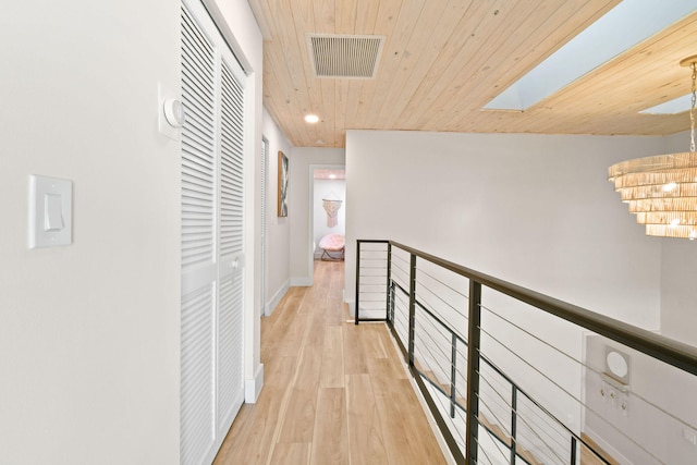 hall with wood ceiling, a skylight, and light hardwood / wood-style floors