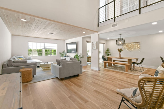 living room with a towering ceiling, wood ceiling, hardwood / wood-style flooring, and a chandelier