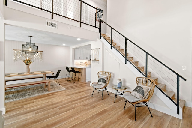 sitting room with a towering ceiling, light hardwood / wood-style flooring, and a chandelier