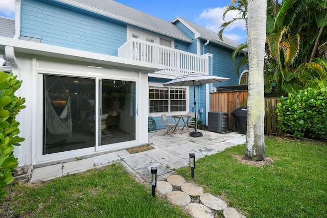 rear view of house featuring a balcony, a lawn, a patio area, and central AC unit