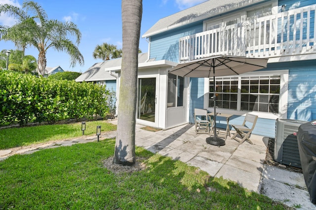 back of house with a balcony, a yard, a patio area, and central AC unit