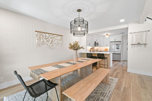 dining area with an inviting chandelier, light hardwood / wood-style flooring, and beam ceiling