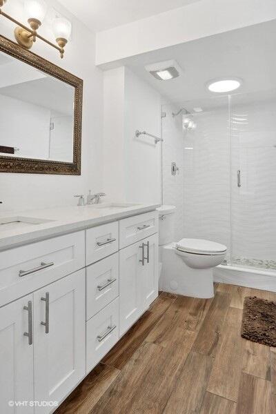 bathroom with vanity, toilet, hardwood / wood-style flooring, and walk in shower