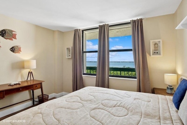 bedroom featuring wood-type flooring and a water view