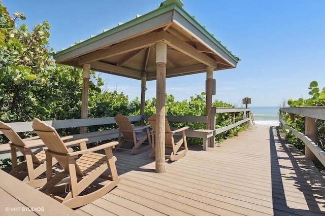 wooden deck featuring a gazebo, a view of the beach, and a water view