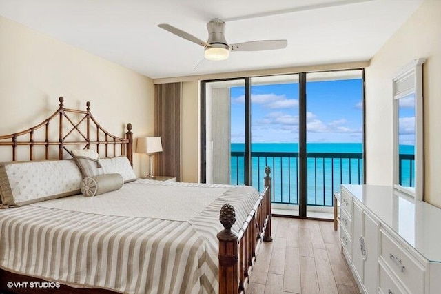 bedroom with light hardwood / wood-style flooring, floor to ceiling windows, access to exterior, ceiling fan, and a water view