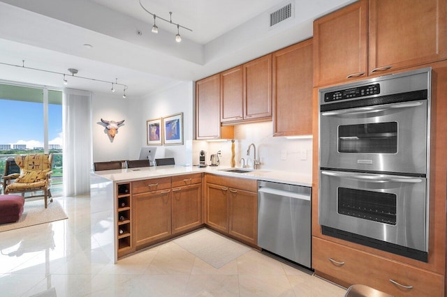 kitchen featuring rail lighting, sink, kitchen peninsula, and stainless steel appliances