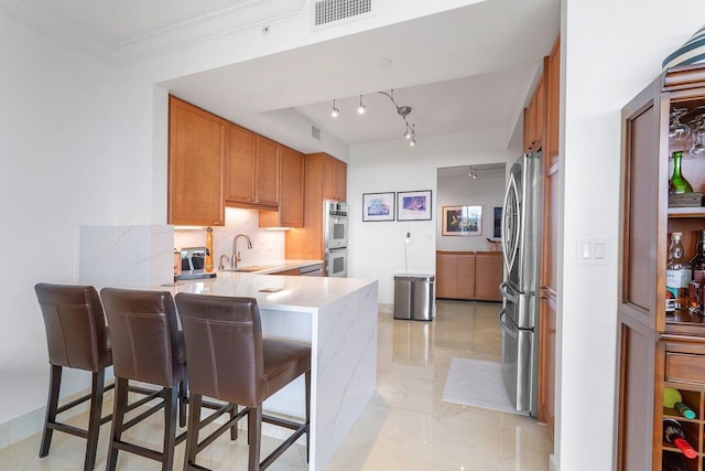 kitchen with a breakfast bar, sink, ornamental molding, double oven, and kitchen peninsula