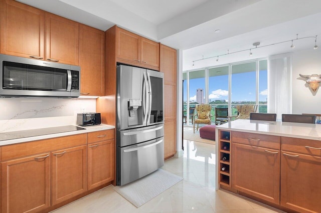 kitchen featuring stainless steel appliances, rail lighting, and decorative backsplash