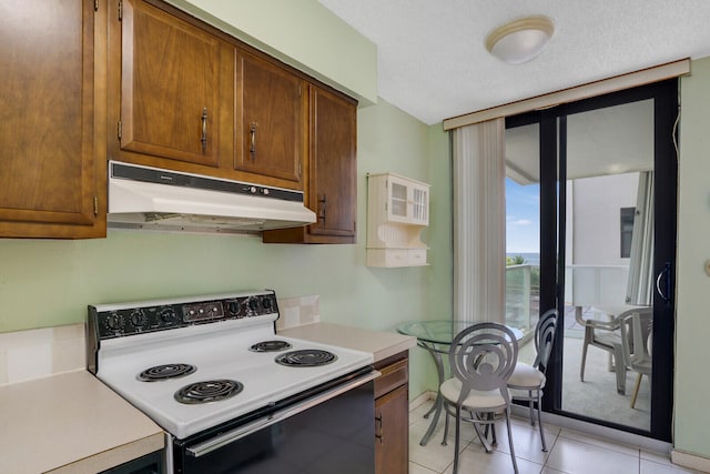 kitchen featuring a textured ceiling, light tile patterned flooring, and electric range