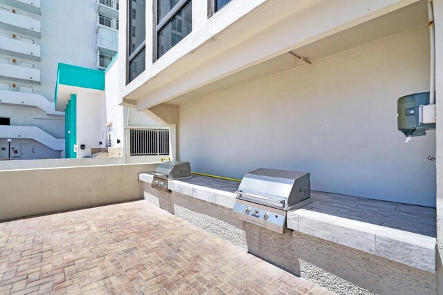 view of patio with a balcony, an outdoor kitchen, and a grill