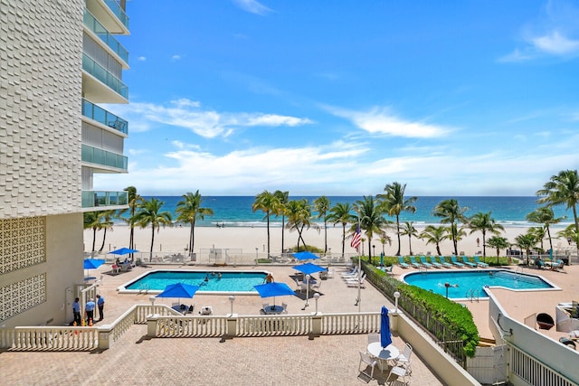 view of swimming pool featuring a patio area, a view of the beach, and a water view