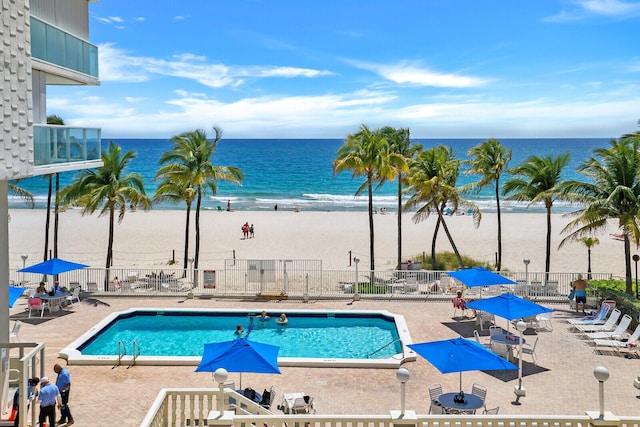 view of pool with a beach view, a water view, and a patio area