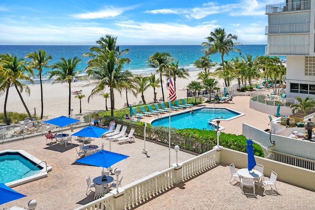 view of swimming pool featuring a view of the beach, a water view, and a patio area