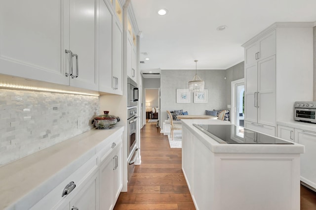 kitchen featuring dark wood-type flooring, white cabinets, hanging light fixtures, a kitchen island, and black electric cooktop