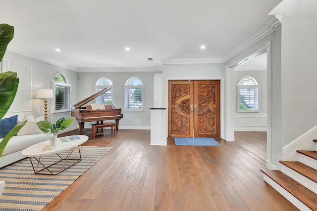 foyer entrance with crown molding and light hardwood / wood-style flooring