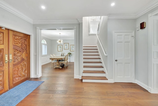 foyer with wood-type flooring, a chandelier, and crown molding