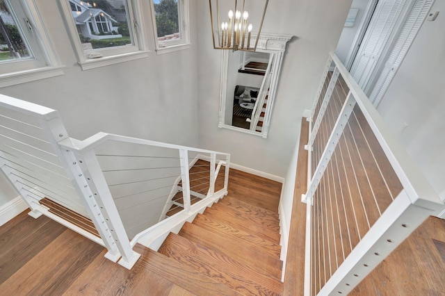 stairs featuring wood-type flooring and a chandelier