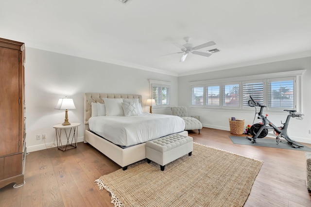 bedroom featuring multiple windows, ornamental molding, ceiling fan, and hardwood / wood-style flooring