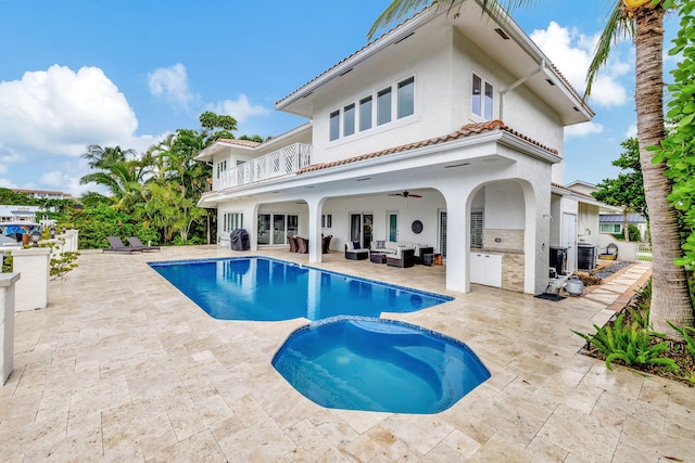 rear view of house with a patio, a balcony, an outdoor living space, a pool with hot tub, and ceiling fan