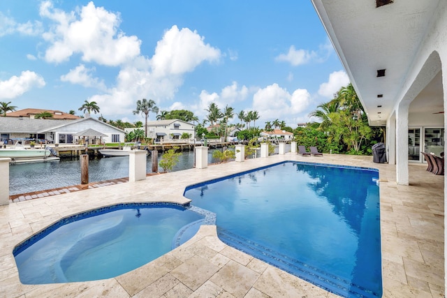 view of pool with an in ground hot tub, a water view, and a patio area