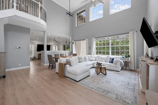 living room featuring a towering ceiling, light hardwood / wood-style flooring, and ceiling fan