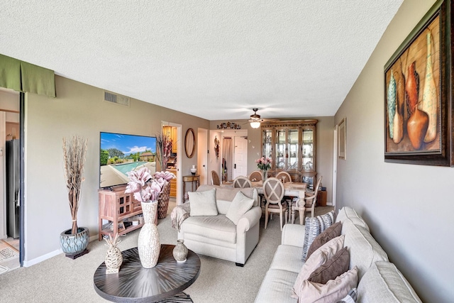 carpeted living room with ceiling fan and a textured ceiling