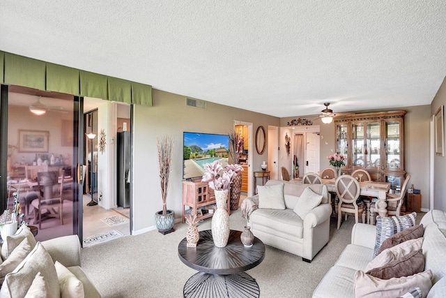 carpeted living room with a textured ceiling and ceiling fan