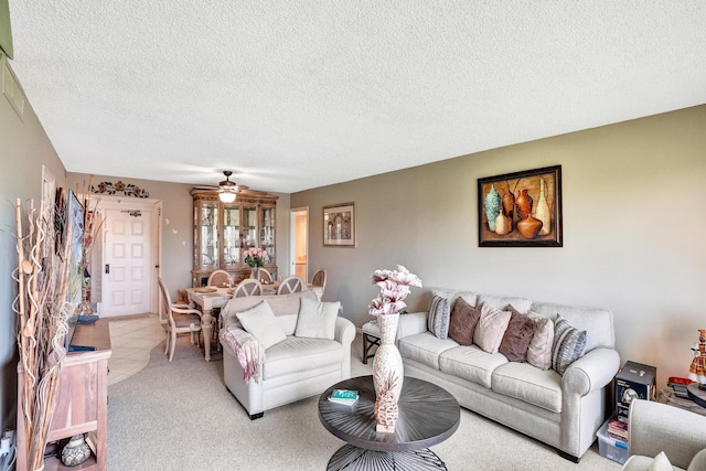 living room featuring light carpet, ceiling fan, and a textured ceiling