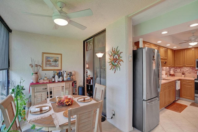 tiled dining space with ceiling fan and a textured ceiling