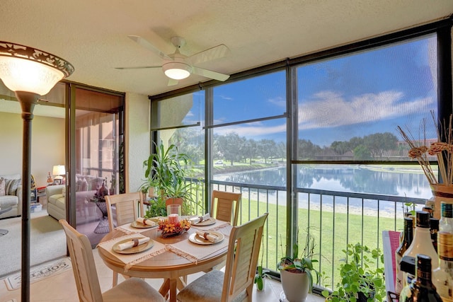 sunroom / solarium with a water view and ceiling fan