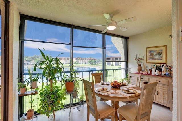 dining room with floor to ceiling windows, ceiling fan, light tile patterned floors, a textured ceiling, and a water view