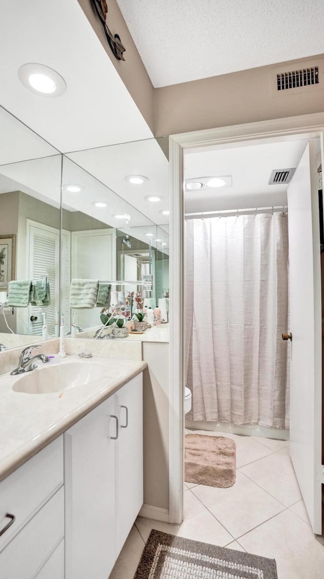 full bathroom featuring vanity, tile patterned floors, toilet, shower / bath combo with shower curtain, and a textured ceiling